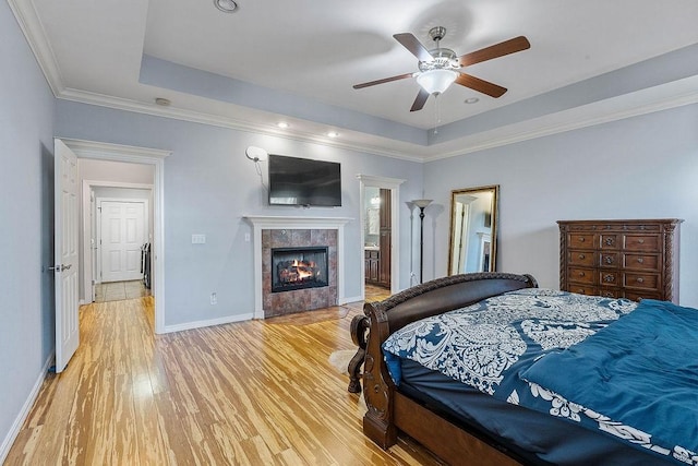 4206 NE Kenton Ave, Bentonville, AR 72712 - bedroom featuring light wood-style flooring, a tray ceiling, a tile fireplace, baseboards, and crown molding