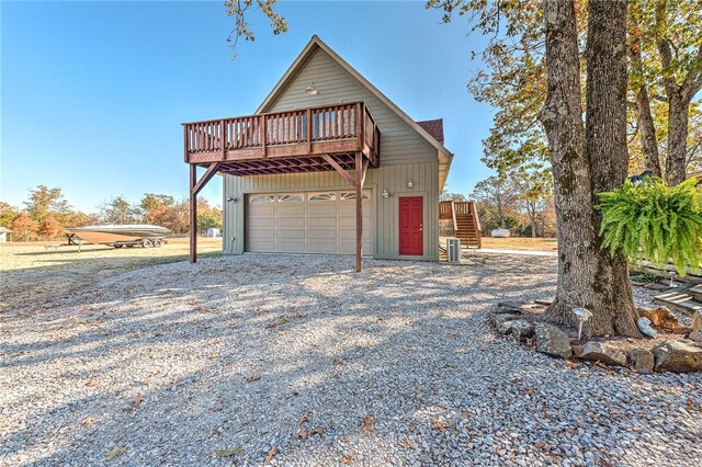 14620 Ravenwood Ln, Garfield, AR 72732 - view of front facade featuring gravel driveway, a wooden deck, stairs, and a garage
