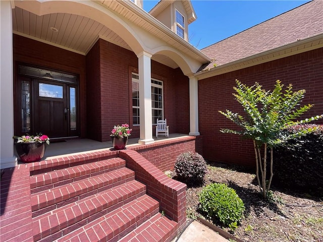 10059 Birdie St, Dardanelle, AR 72834 - view of exterior entry with covered porch, brick siding, and a shingled roof