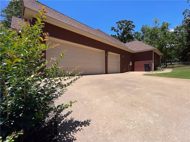 10059 Birdie St, Dardanelle, AR 72834 - view of side of home featuring an attached garage, driveway, brick siding, and a shingled roof