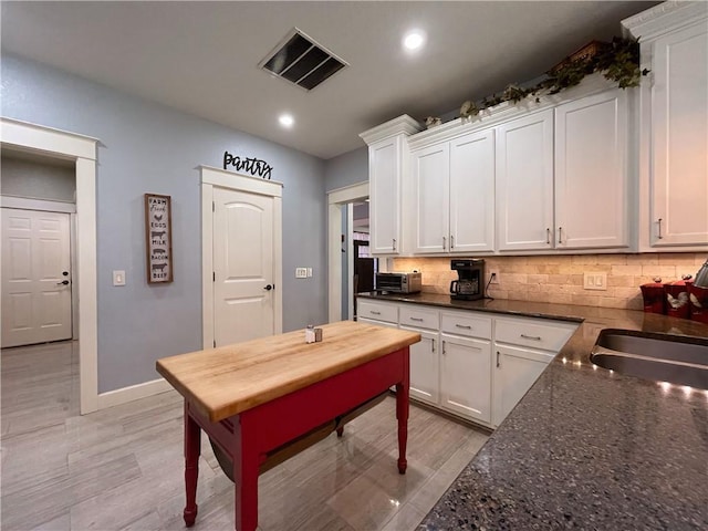 10059 Birdie St, Dardanelle, AR 72834 - kitchen featuring white cabinetry, decorative backsplash, baseboards, recessed lighting, and light wood-style floors