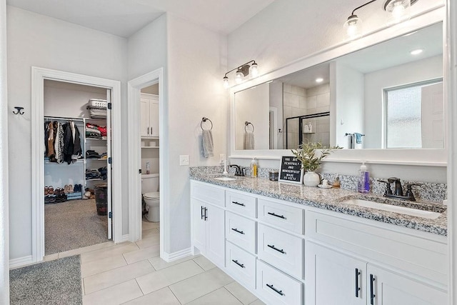 1904 Bergman Rd, Pea Ridge, AR 72751 - bathroom featuring a shower stall, double vanity, toilet, a walk in closet, and tile patterned floors