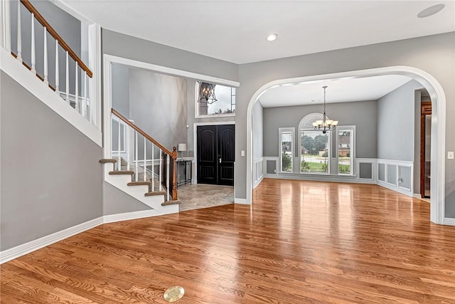 2707 W Lilac St, Rogers, AR 72758 - foyer featuring a chandelier, arched walkways, wood finished floors, stairway, and a decorative wall