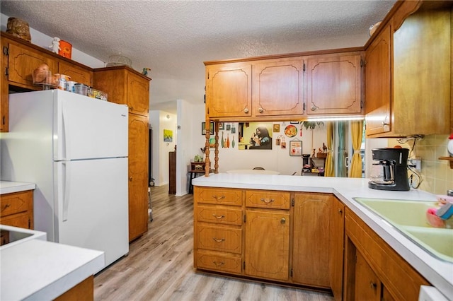 5 Chapel Ln, Bella Vista, AR 72715 - kitchen with freestanding refrigerator, brown cabinetry, light countertops, and a textured ceiling
