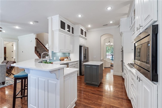 5203 SW Newcastle Rd, Bentonville, AR 72713 - kitchen featuring stainless steel appliances, crown molding, decorative backsplash, a peninsula, and glass insert cabinets