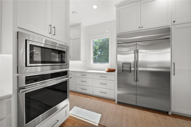 10393 Cedar Rock Rd, Garfield, AR 72732 - kitchen featuring built in appliances, light wood-style floors, white cabinets, light countertops, and recessed lighting