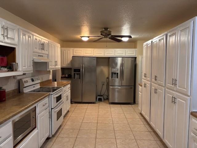 12883 Nickels Rd, West Fork, AR 72774 - kitchen featuring appliances with stainless steel finishes, a ceiling fan, under cabinet range hood, light tile patterned floors, and white cabinetry