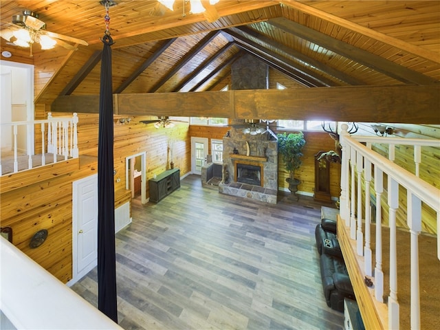 12883 Nickels Rd, West Fork, AR 72774 - unfurnished living room featuring wooden walls, ceiling fan, wood finished floors, wood ceiling with exposed beams, and an outdoor stone fireplace