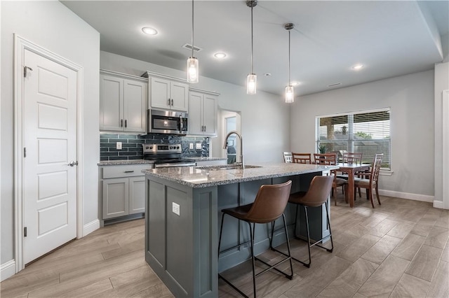 483 N Otoe St, Farmington, AR 72730 - kitchen with stainless steel appliances, a sink, baseboards, light wood-style floors, and light stone counters