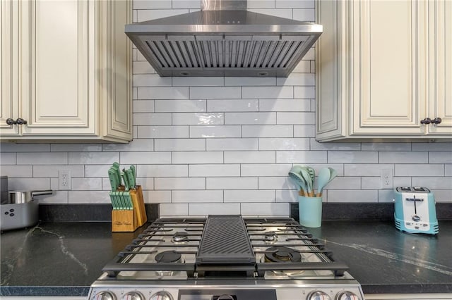 12698 Bush Rd, Centerton, AR 72719 - kitchen featuring range hood, tasteful backsplash, cream cabinetry, stainless steel gas cooktop, and dark stone counters