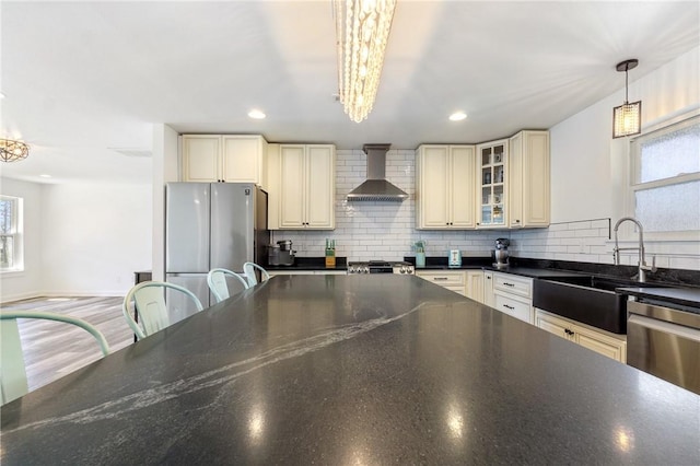 12698 Bush Rd, Centerton, AR 72719 - kitchen featuring cream cabinets, wall chimney range hood, appliances with stainless steel finishes, a sink, and decorative backsplash