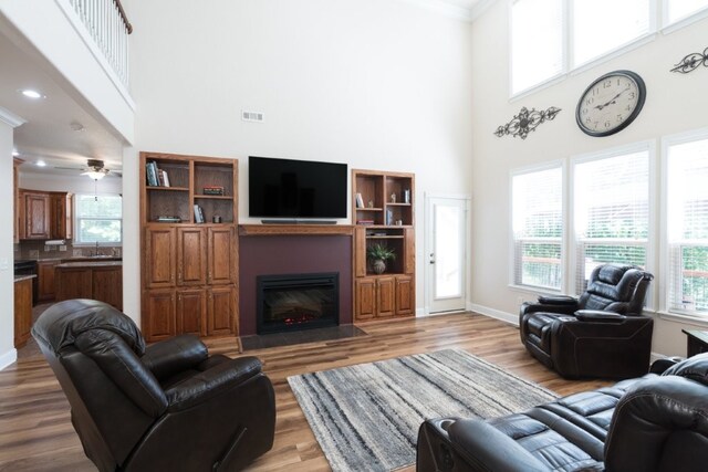 15210 Haynes Rd, Rogers, AR 72756 - living area featuring a high ceiling, a fireplace with flush hearth, wood finished floors, baseboards, and ornamental molding