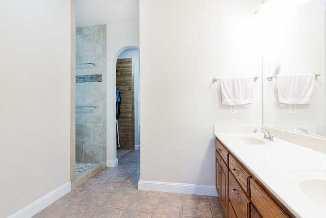 15210 Haynes Rd, Rogers, AR 72756 - bathroom featuring double vanity, a tile shower, tile patterned flooring, baseboards, and a spacious closet