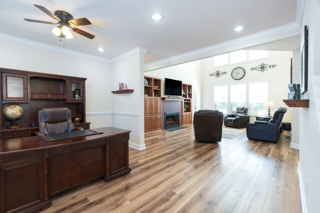 15210 Haynes Rd, Rogers, AR 72756 - home office with a glass covered fireplace, ceiling fan, crown molding, light wood-style flooring, and baseboards