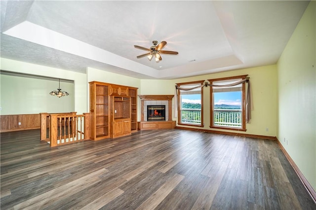 17 La Costa Dr, Holiday Island, AR 72631 - unfurnished living room with a raised ceiling, dark wood-type flooring, ceiling fan, a tile fireplace, and baseboards