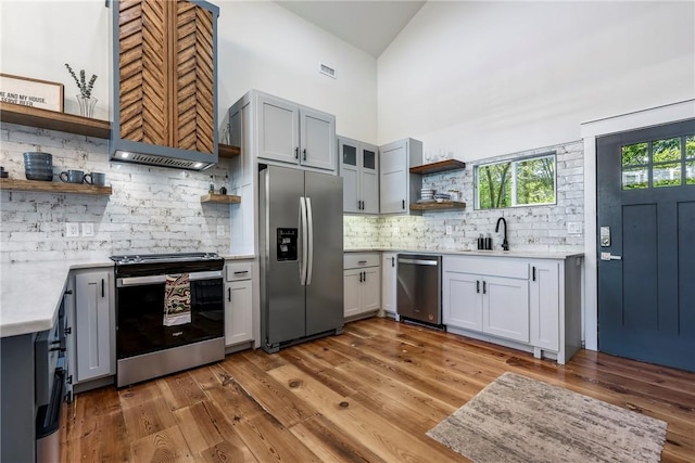 327 S E Ave, Fayetteville, AR 72701 - kitchen featuring stainless steel appliances, open shelves, premium range hood, backsplash, and light wood-style flooring