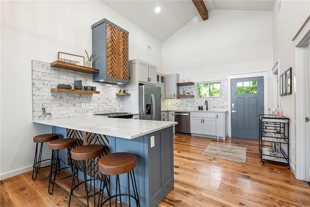 327 S E Ave, Fayetteville, AR 72701 - kitchen featuring open shelves, stainless steel appliances, a kitchen breakfast bar, a peninsula, and high vaulted ceiling