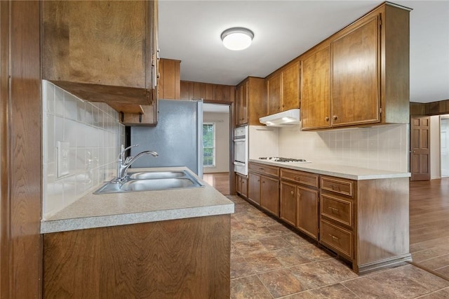 5 Rolling Meadows Dr, Harrison, AR 72601 - kitchen featuring a sink, white appliances, a warming drawer, brown cabinets, and under cabinet range hood