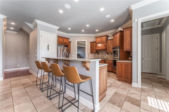 2314 S The Peaks Blvd, Rogers, AR 72758 - kitchen featuring appliances with stainless steel finishes, brown cabinets, ornamental molding, backsplash, and premium range hood