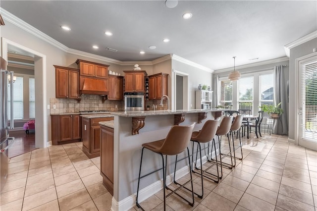 2314 S The Peaks Blvd, Rogers, AR 72758 - kitchen with stainless steel appliances, brown cabinetry, custom range hood, a large island, and healthy amount of natural light