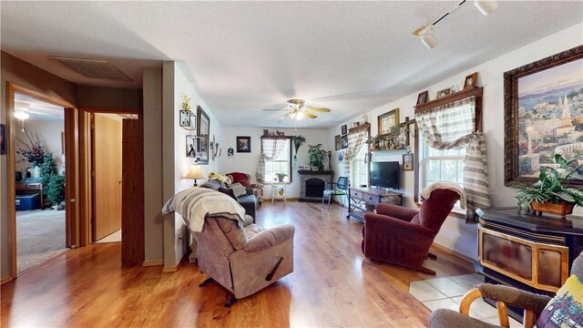 15829 N Wimpy Jones Rd, Garfield, AR 72732 - living area featuring light wood finished floors, a wood stove, ceiling fan, a textured ceiling, and baseboards