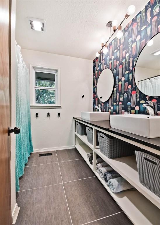 1463 E Woodbrook Dr, Fayetteville, AR 72703 - bathroom with double vanity, tile patterned flooring, baseboards, and a textured ceiling
