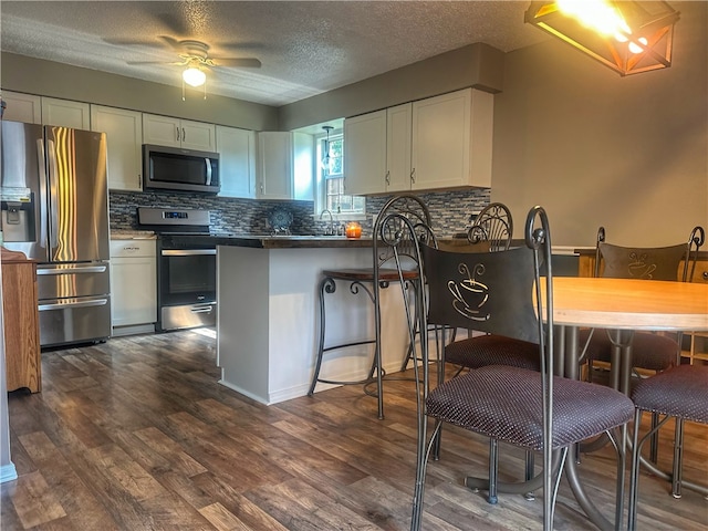 3002 W 4th St, Russellville, AR 72801 - kitchen with stainless steel appliances, a peninsula, white cabinets, backsplash, and a textured ceiling