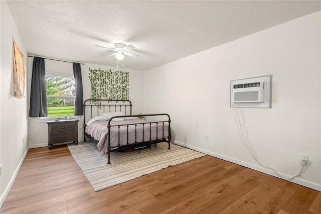 3307 NW 3rd St, Bentonville, AR 72712 - bedroom featuring light wood-style flooring, baseboards, a wall mounted air conditioner, and a ceiling fan