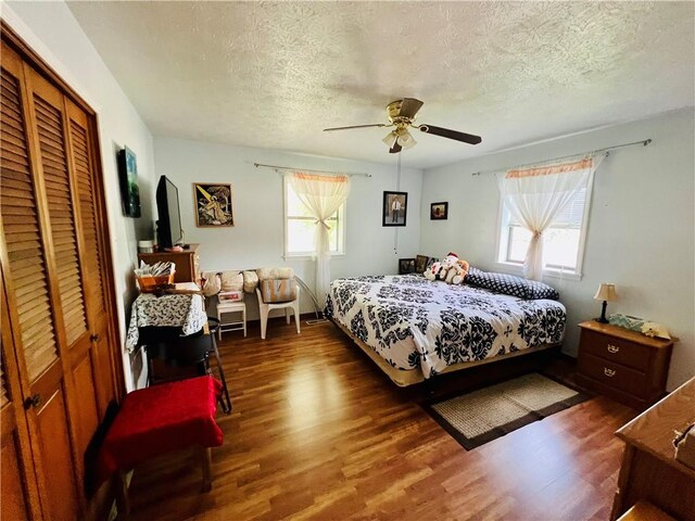 720 Circle Dr, Berryville, AR 72616 - bedroom with wood finished floors, a textured ceiling, a closet, and a ceiling fan