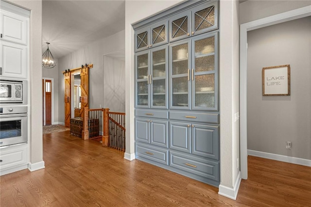 42 Devizis Dr, Bella Vista, AR 72714 - hallway with a barn door, an upstairs landing, wood finished floors, and a chandelier