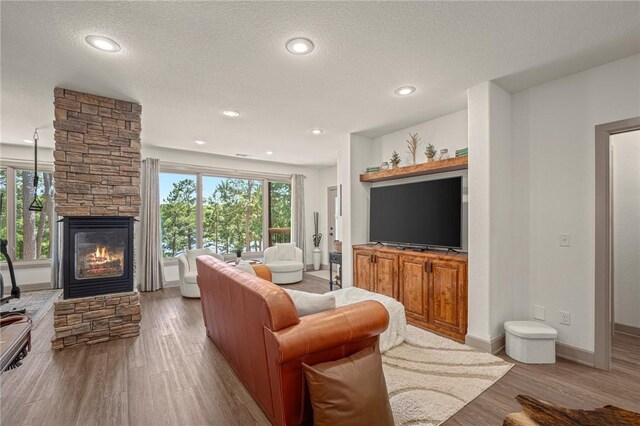 42 Devizis Dr, Bella Vista, AR 72714 - living area featuring wood finished floors, a stone fireplace, baseboards, a textured ceiling, and recessed lighting