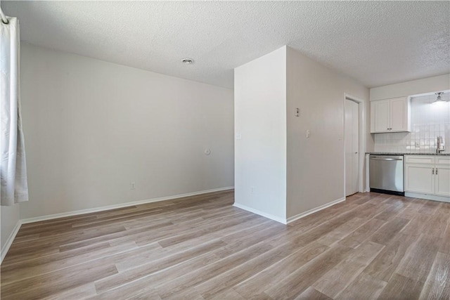 3021-3023 N Old Missouri Rd, Fayetteville, AR 72703 - kitchen with stainless steel dishwasher, light wood-style flooring, white cabinets, decorative backsplash, and a textured ceiling