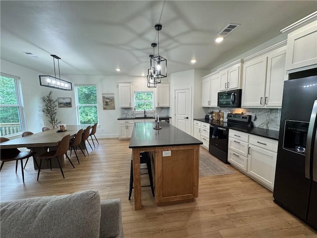 1 Llanon Cir, Bella Vista, AR 72714 - kitchen with black appliances, dark countertops, backsplash, recessed lighting, and light wood finished floors
