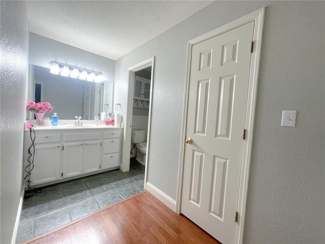 405-407 Rena Rd, Van Buren, AR 72956 - bathroom with a textured wall, toilet, vanity, baseboards, and wood finished floors