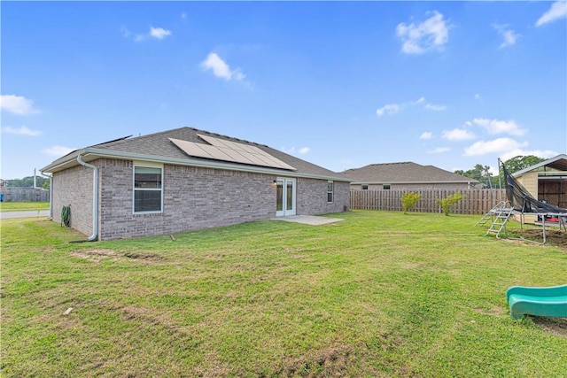 200 Post Oak Ave, Gentry, AR 72734 - rear view of property with a trampoline, roof mounted solar panels, french doors, brick siding, and a playground