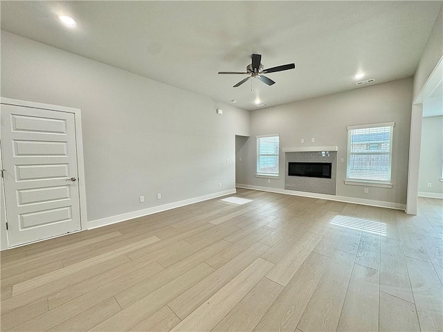 480 S Benchmark Ln, Fayetteville, AR 72704 - unfurnished living room featuring a ceiling fan, light wood-style flooring, a tiled fireplace, and baseboards