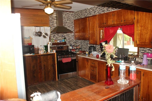 197 7th St, Saint Paul, AR 72756 - kitchen with wall chimney exhaust hood, stainless steel range with gas cooktop, decorative backsplash, a ceiling fan, and brown cabinetry
