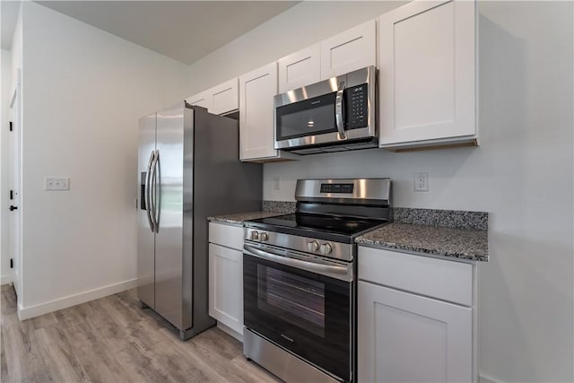 1071 Kentucky Ave, Bentonville, AR 72713 - kitchen with stainless steel appliances, light wood-style floors, baseboards, white cabinets, and dark stone counters