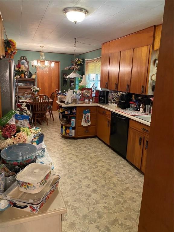 924 W Ave, Lincoln, AR 72744 - kitchen with freestanding refrigerator, black dishwasher, brown cabinets, light countertops, and a chandelier