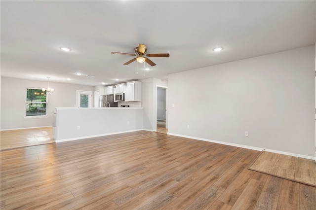 1505 S K Pl, Rogers, AR 72756 - unfurnished living room with ceiling fan, a chandelier, recessed lighting, light wood-style flooring, and baseboards