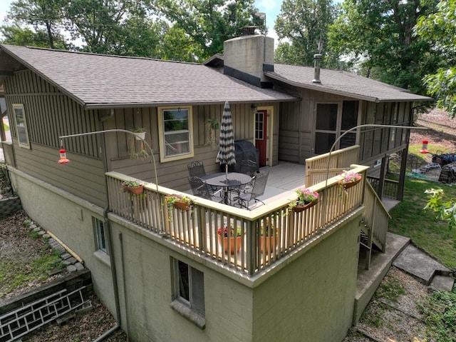 122 Hillcrest Rd, Eureka Springs, AR 72631 - rear view of house featuring a chimney, a wooden deck, outdoor dining area, a shingled roof, and board and batten siding
