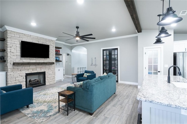 1909 Crump St, Pea Ridge, AR 72751 - living area with arched walkways, light wood-type flooring, a ceiling fan, a stone fireplace, and baseboards