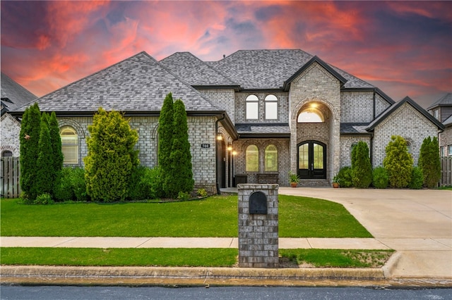 700 SE Yale St, Bentonville, AR 72712 - french country inspired facade with brick siding, french doors, roof with shingles, and driveway