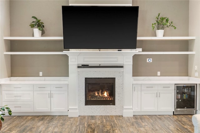 700 SE Yale St, Bentonville, AR 72712 - unfurnished living room featuring beverage cooler, light wood-style floors, and a glass covered fireplace