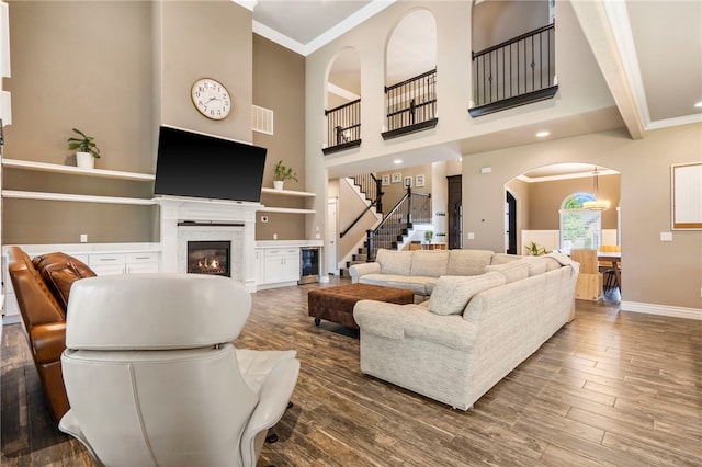 700 SE Yale St, Bentonville, AR 72712 - living area featuring crown molding, a glass covered fireplace, stairs, arched walkways, and wood finished floors