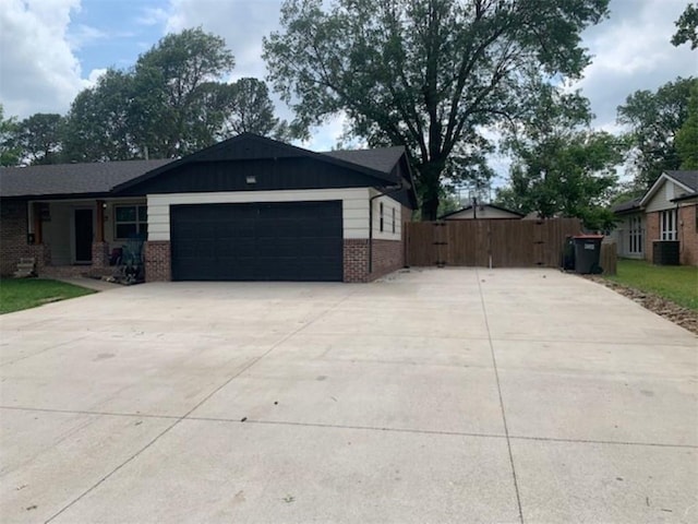 712 Carlton St, Springdale, AR 72762 - view of front of home with a garage, concrete driveway, brick siding, a gate, and central AC unit