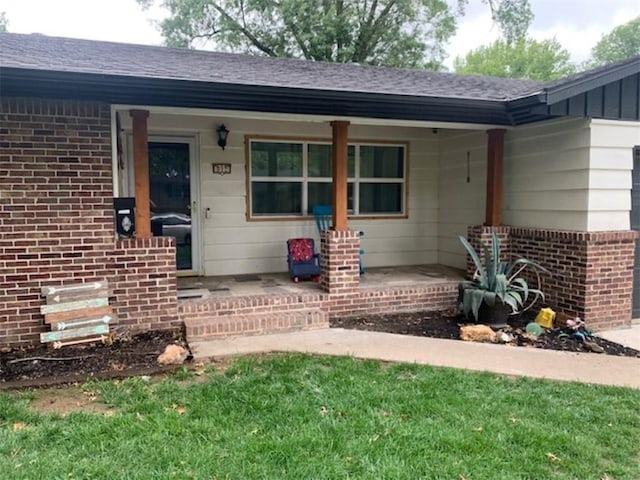 712 Carlton St, Springdale, AR 72762 - view of exterior entry with covered porch, brick siding, and a shingled roof
