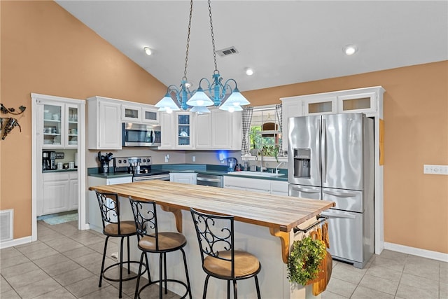 9225 Charles St, Rogers, AR 72756 - kitchen with butcher block countertops, appliances with stainless steel finishes, white cabinetry, a breakfast bar, and light tile patterned floors