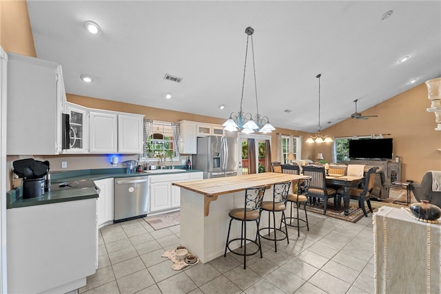 9225 Charles St, Rogers, AR 72756 - kitchen featuring stainless steel appliances, a breakfast bar area, a ceiling fan, light tile patterned floors, and healthy amount of natural light