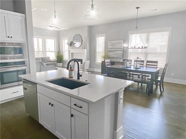 1432 Cannon Ln, Cave Springs, AR 72718 - kitchen featuring stainless steel appliances, open floor plan, a kitchen island with sink, light countertops, and a premium fireplace